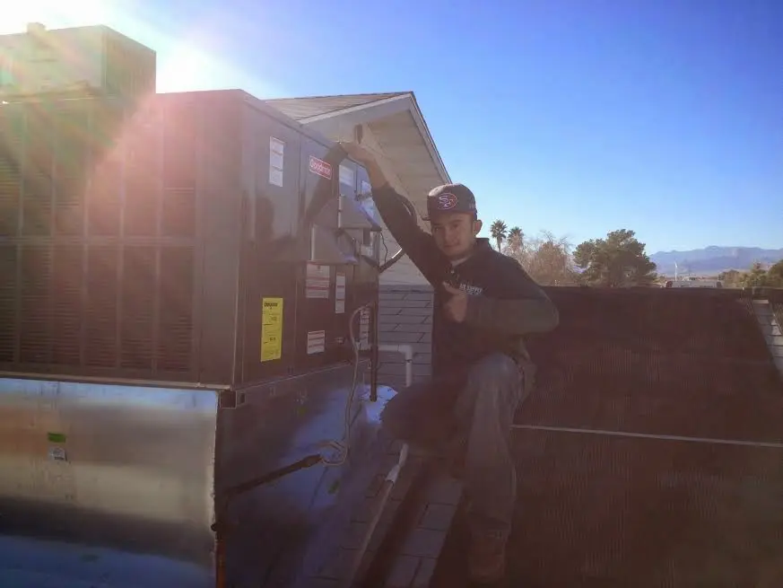 HVAC technician performing Air Duct Cleaning on a rooftop unit in Dorr